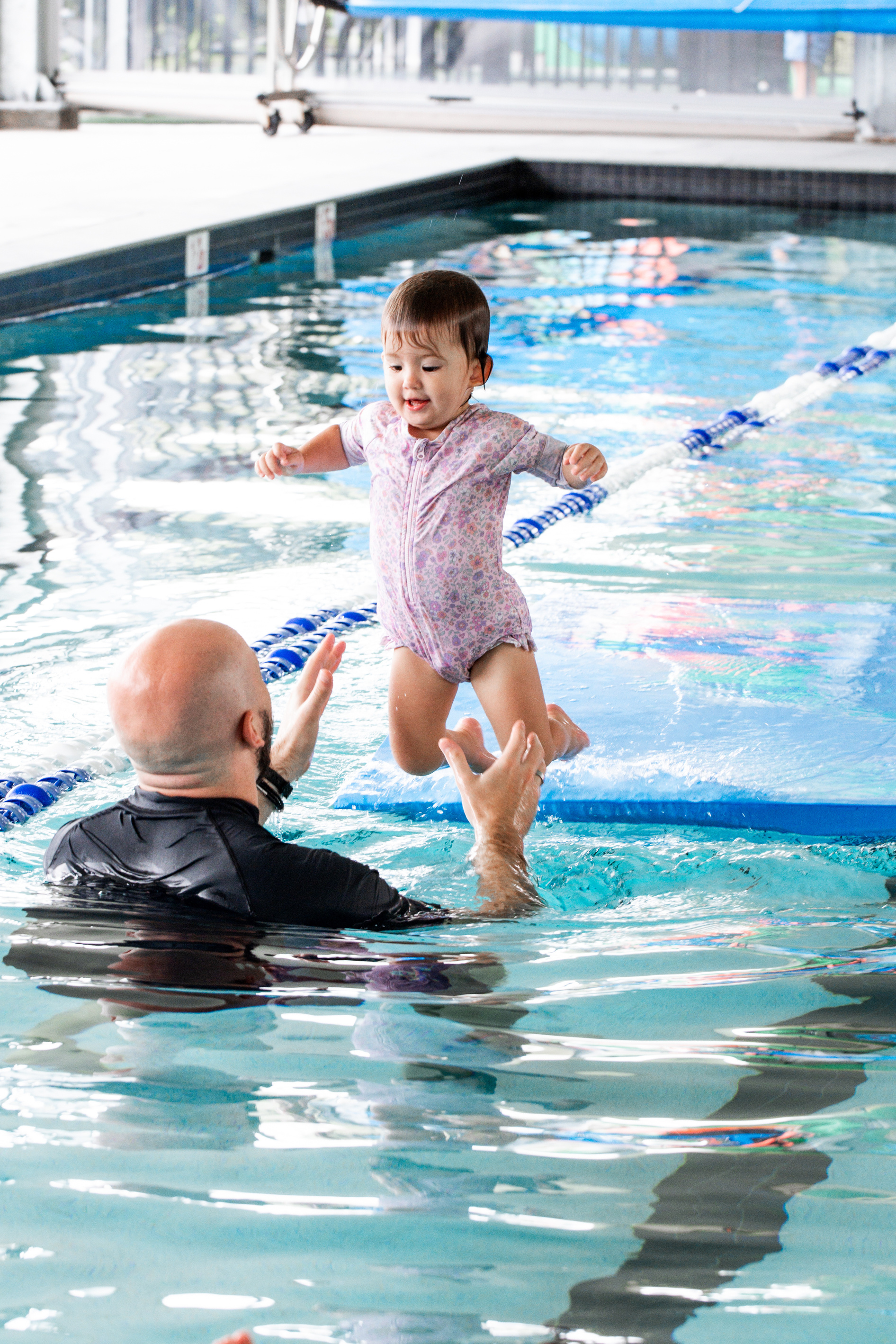 A young child enjoying a swimming lesson with an instructor
